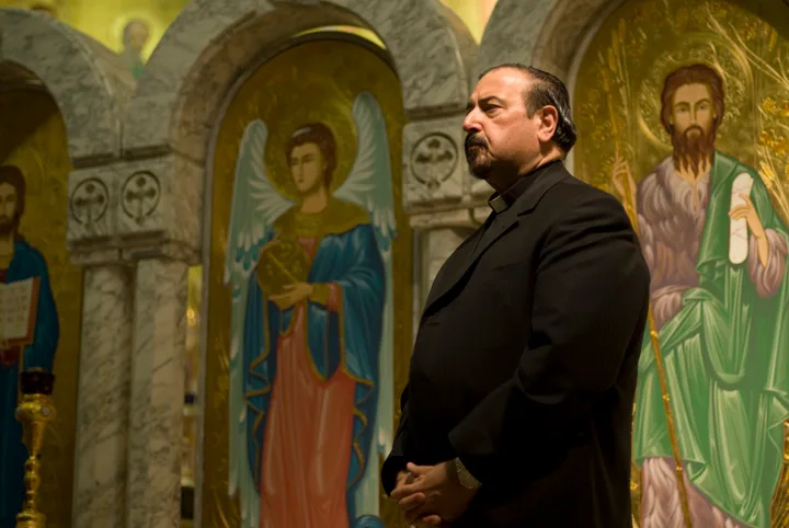 Fr. Joseph Antypas seated and listening, with the iconostasis of St. George behind him