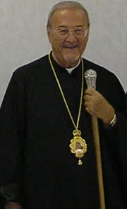 Metropolitan Philip in black monastic dress wearing a panagia, holding a microphone
