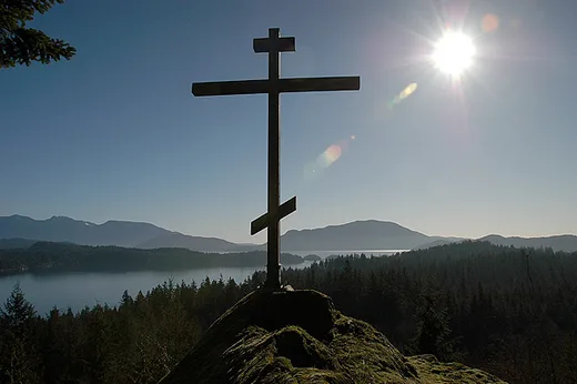 A Russian Orthodox three-bar cross silhouetted against an Alaskan sky