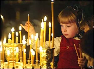 A young girl lighting a votive candle before an icon